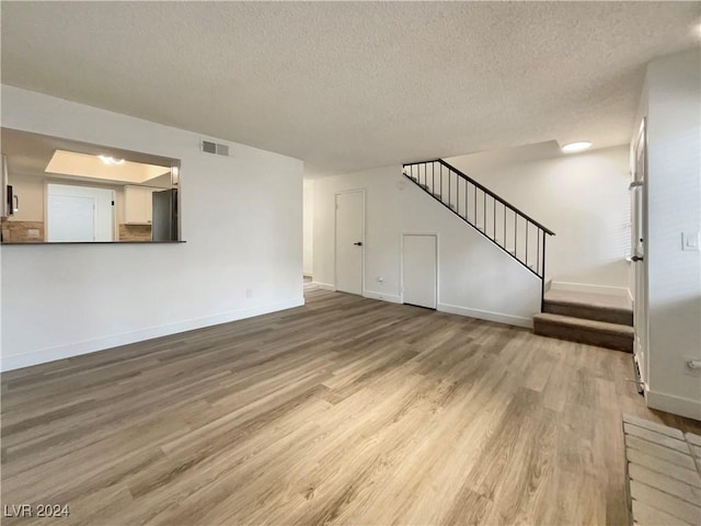 unfurnished living room featuring wood-type flooring and a textured ceiling