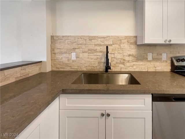 kitchen with white cabinetry, stainless steel dishwasher, dark stone counters, and sink