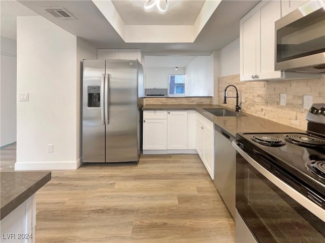 kitchen with sink, white cabinets, light hardwood / wood-style floors, and appliances with stainless steel finishes