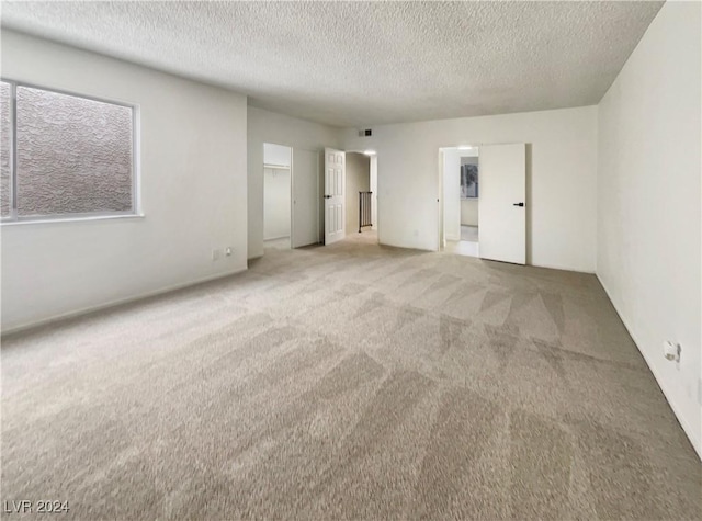 unfurnished bedroom with carpet flooring, a textured ceiling, a closet, and a walk in closet