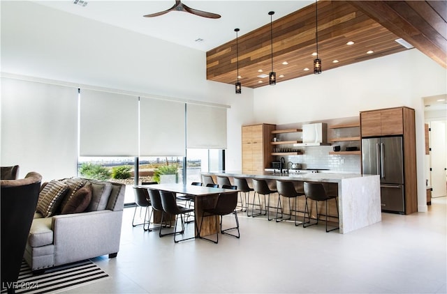 dining area featuring ceiling fan, sink, wooden ceiling, and a high ceiling