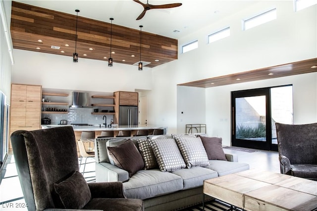 living room with ceiling fan, sink, and a high ceiling