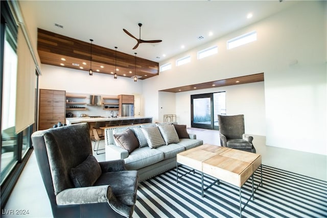 living room with ceiling fan and a high ceiling