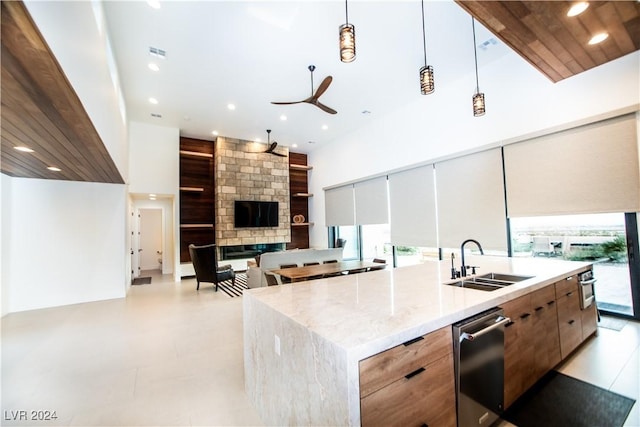 kitchen with sink, a high ceiling, decorative light fixtures, a fireplace, and a center island with sink