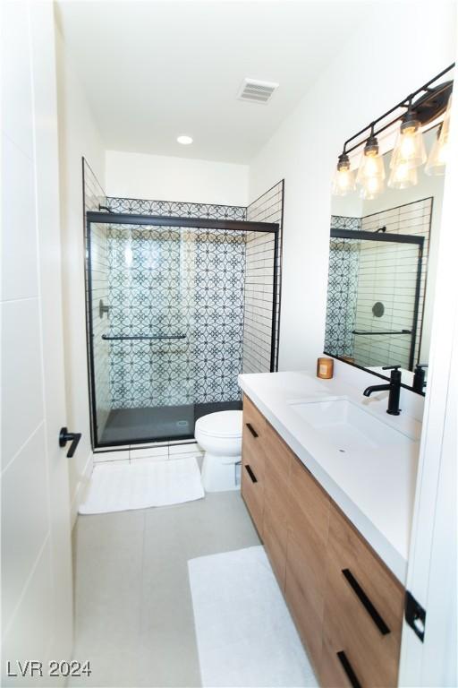 bathroom with tile patterned flooring, vanity, a shower with shower door, and toilet