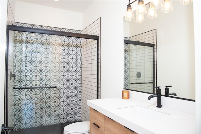 bathroom featuring vanity, toilet, and a shower with door