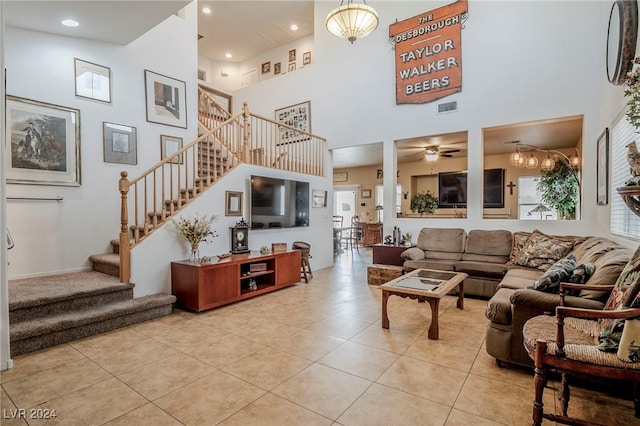 living room with ceiling fan with notable chandelier, light tile patterned flooring, and a high ceiling