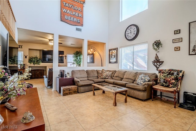 tiled living room featuring a high ceiling and ceiling fan with notable chandelier