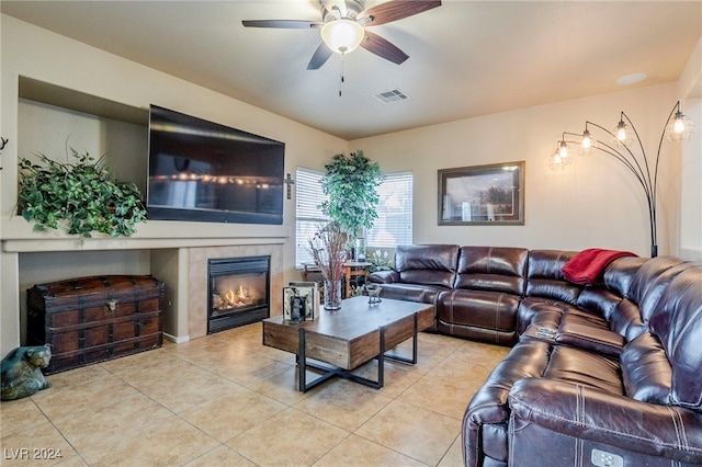 tiled living room with ceiling fan and a tiled fireplace