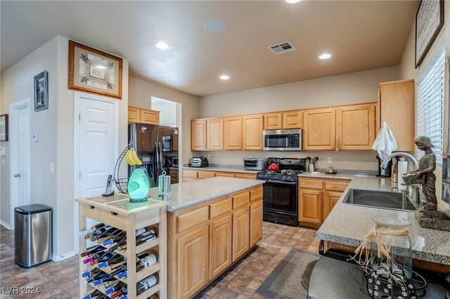 kitchen with sink, light brown cabinets, light stone counters, a kitchen island, and black appliances