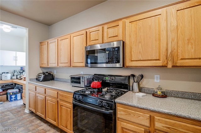 kitchen featuring black range with gas stovetop and light brown cabinetry