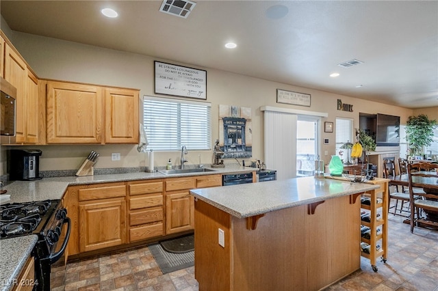 kitchen with sink, a center island, light brown cabinets, a breakfast bar, and black appliances