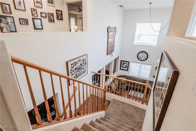 staircase with ceiling fan and a towering ceiling