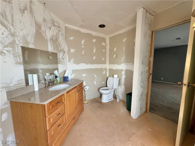 bathroom with vanity, toilet, and concrete floors