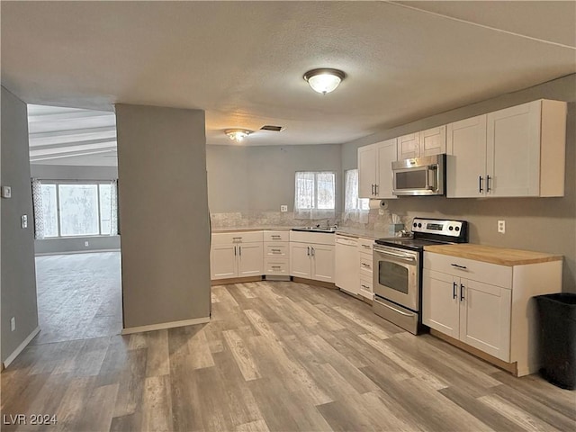 kitchen with plenty of natural light, white cabinets, stainless steel appliances, and light hardwood / wood-style floors