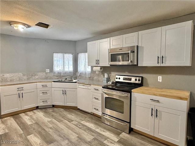 kitchen featuring white cabinets, stainless steel appliances, butcher block counters, and sink