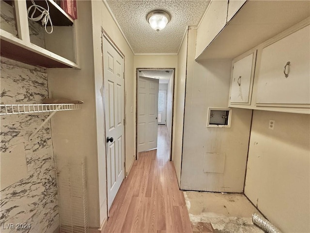 interior space featuring cabinets, washer hookup, crown molding, a textured ceiling, and light wood-type flooring