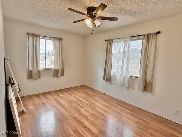 unfurnished room with plenty of natural light, ceiling fan, and light hardwood / wood-style flooring