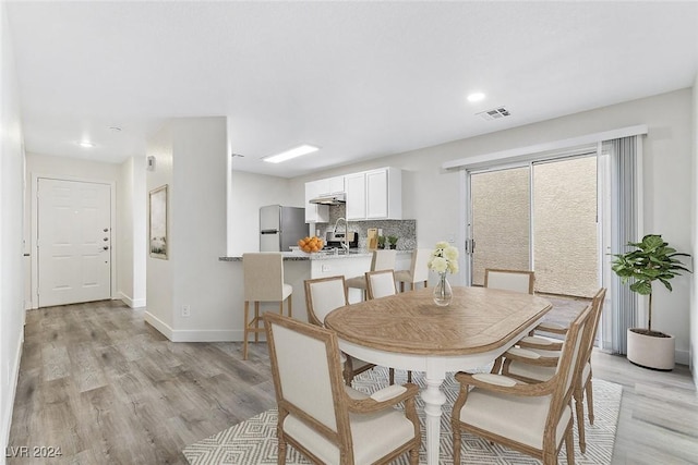 dining area with sink and light wood-type flooring