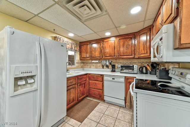 kitchen featuring a paneled ceiling, white appliances, backsplash, sink, and light tile patterned floors