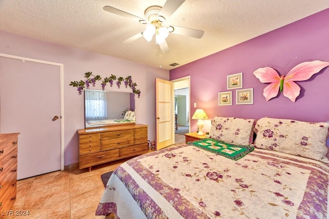 bedroom with a textured ceiling, ceiling fan, and light tile patterned flooring