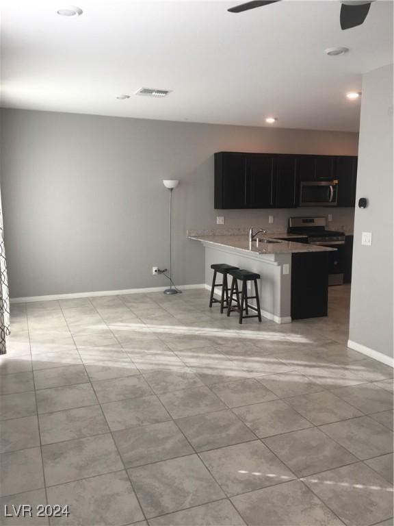 kitchen with a breakfast bar, sink, ceiling fan, kitchen peninsula, and stainless steel appliances