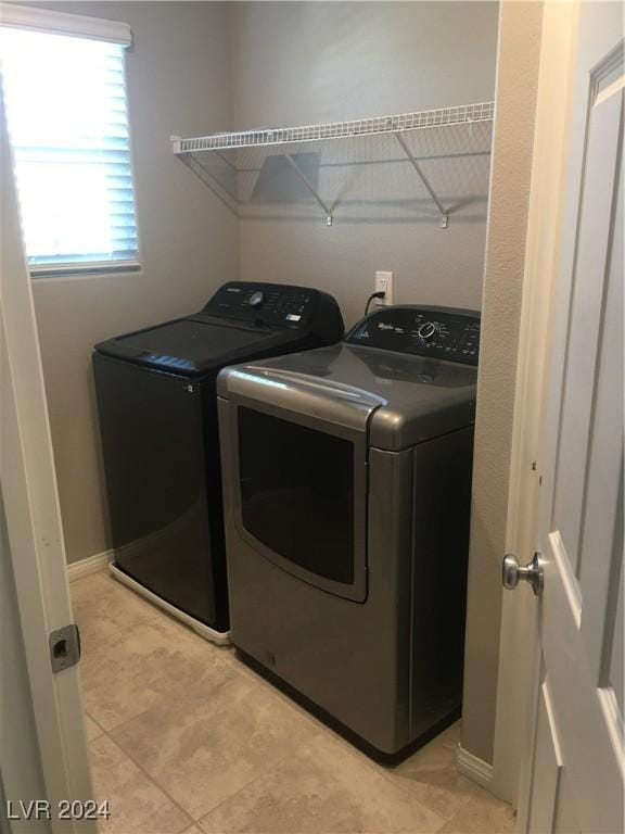 clothes washing area featuring light tile patterned flooring and separate washer and dryer