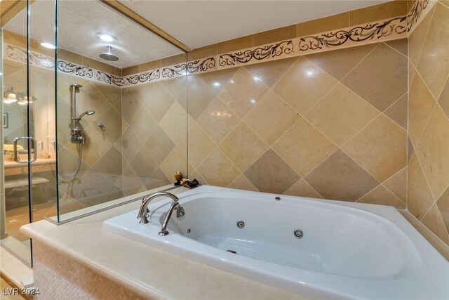 bathroom with tile walls and independent shower and bath