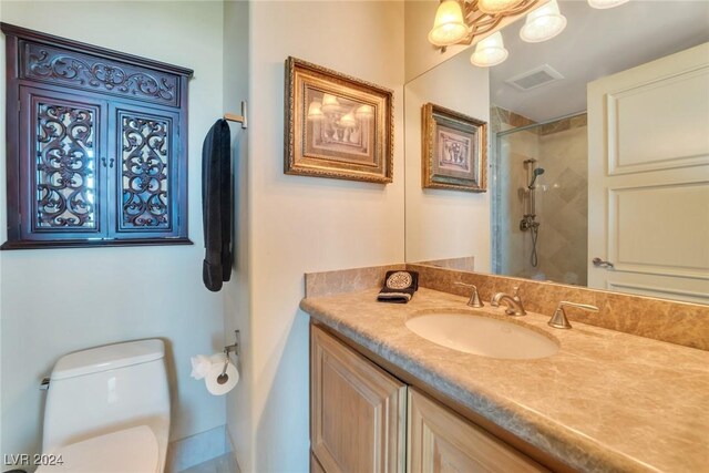 bathroom featuring toilet, vanity, and tiled shower