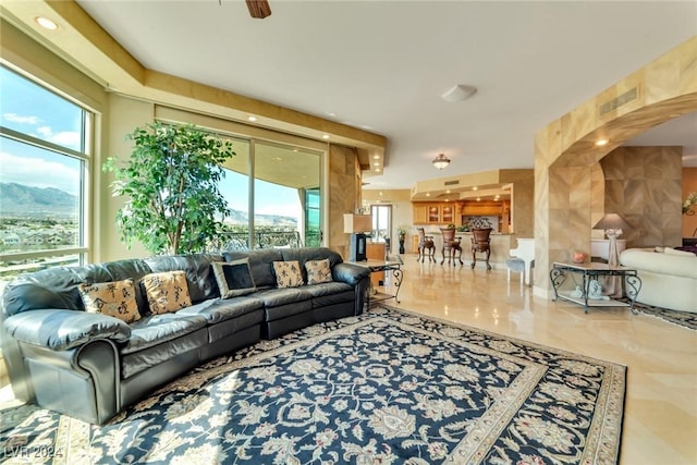 living room with ceiling fan, a mountain view, and a healthy amount of sunlight