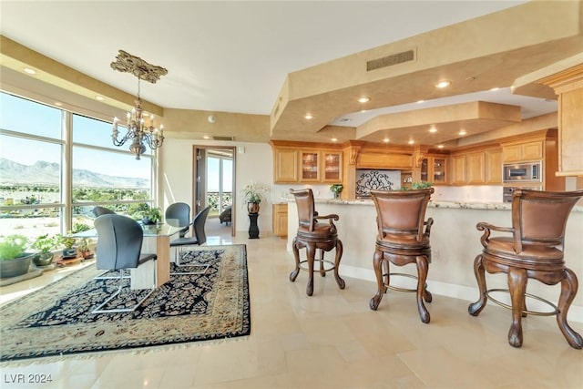 kitchen featuring light stone countertops, stainless steel microwave, a notable chandelier, a mountain view, and decorative light fixtures