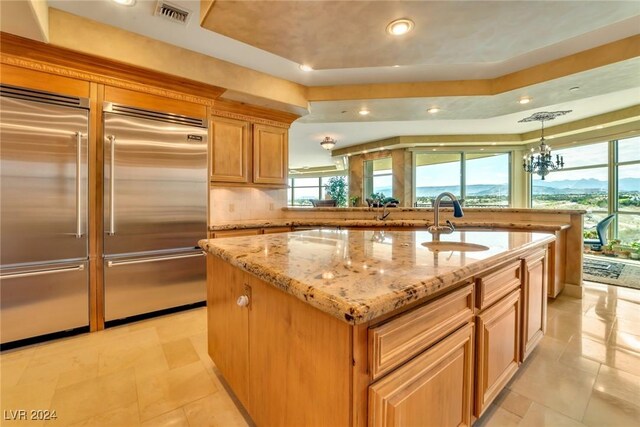 kitchen with an island with sink, a healthy amount of sunlight, and stainless steel built in refrigerator