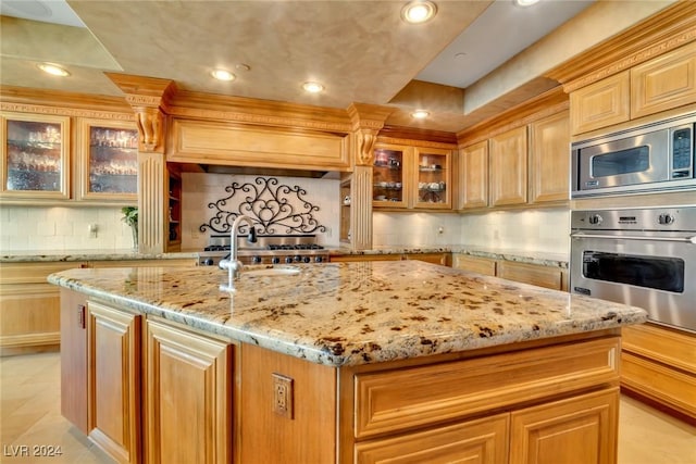 kitchen with premium range hood, decorative backsplash, an island with sink, light stone counters, and stainless steel appliances