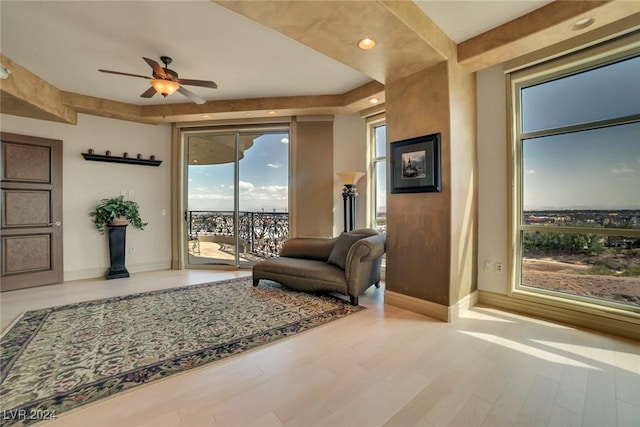 living area with a wealth of natural light, light hardwood / wood-style flooring, and ceiling fan