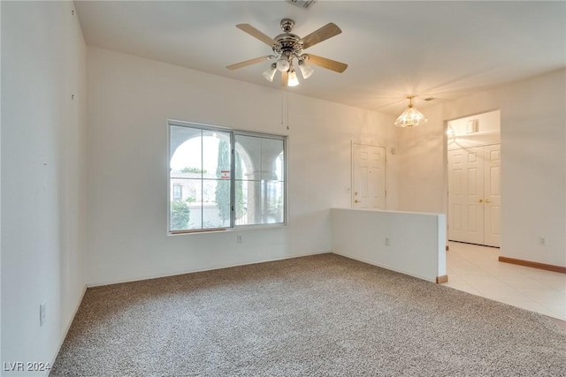 unfurnished room featuring ceiling fan with notable chandelier and light colored carpet