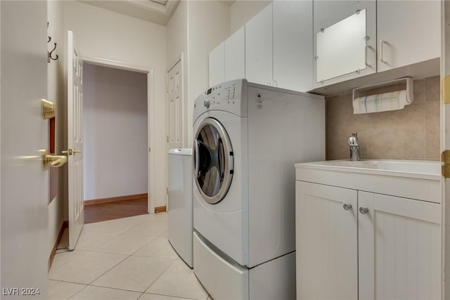 laundry area featuring sink, light tile patterned floors, and cabinets