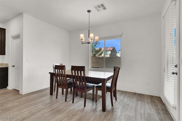 dining area with light hardwood / wood-style flooring and an inviting chandelier