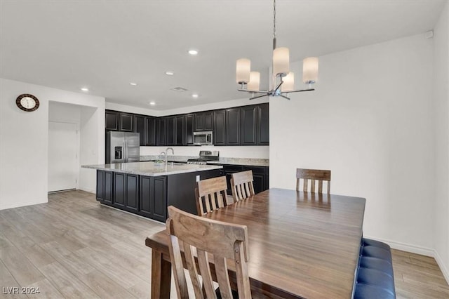 dining space with sink, light hardwood / wood-style floors, and an inviting chandelier