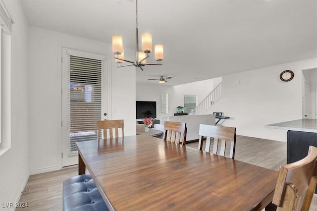 dining room featuring light hardwood / wood-style flooring and ceiling fan with notable chandelier