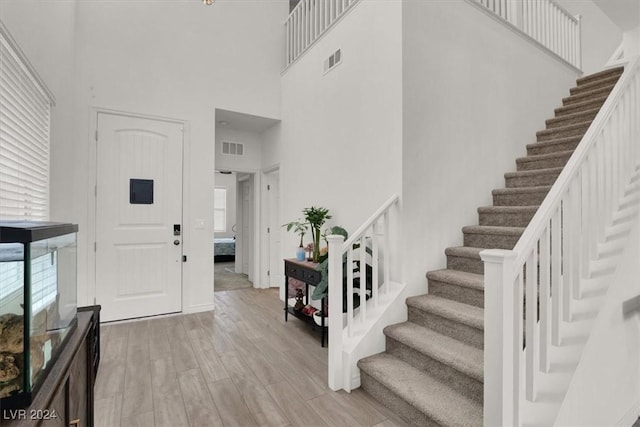 foyer entrance featuring light hardwood / wood-style floors and a towering ceiling