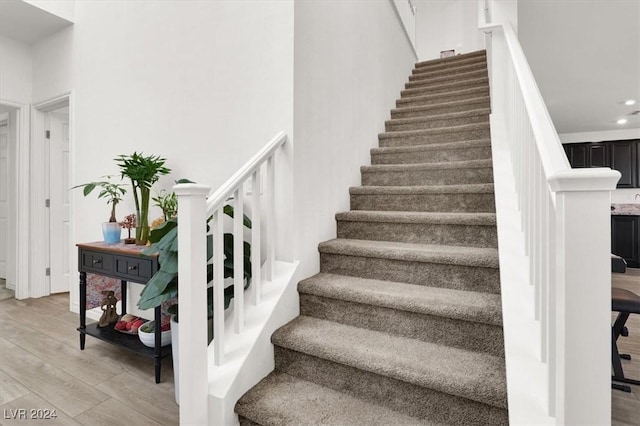 stairs with hardwood / wood-style floors and a towering ceiling