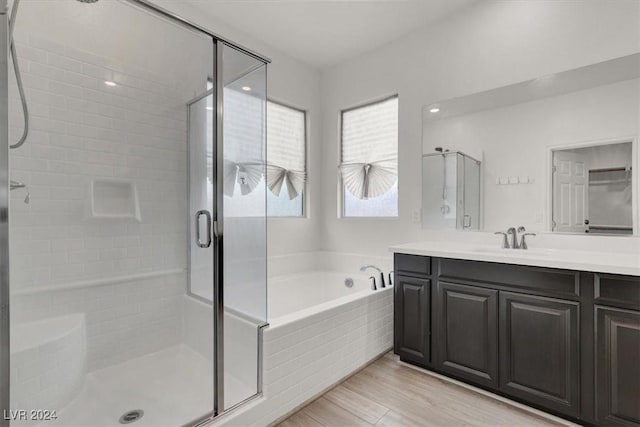 bathroom with vanity, wood-type flooring, and shower with separate bathtub