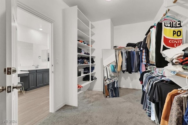 walk in closet featuring light colored carpet and sink