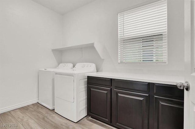 laundry room featuring cabinets, light hardwood / wood-style flooring, and washing machine and clothes dryer