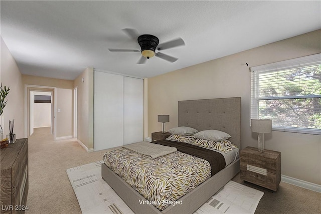 carpeted bedroom with ceiling fan and a closet