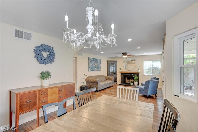 dining area with ceiling fan with notable chandelier and light hardwood / wood-style flooring