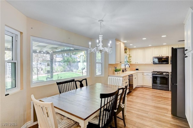 dining area with light hardwood / wood-style floors, an inviting chandelier, and sink