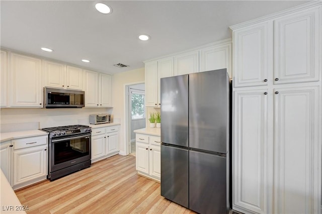 kitchen featuring white cabinets, light wood-type flooring, and appliances with stainless steel finishes