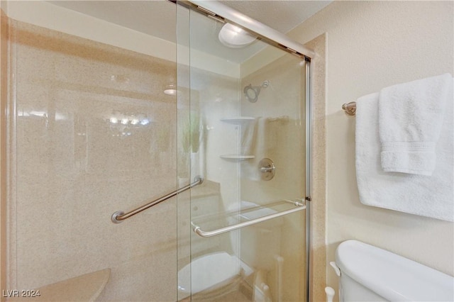 bathroom featuring a shower with shower door and toilet