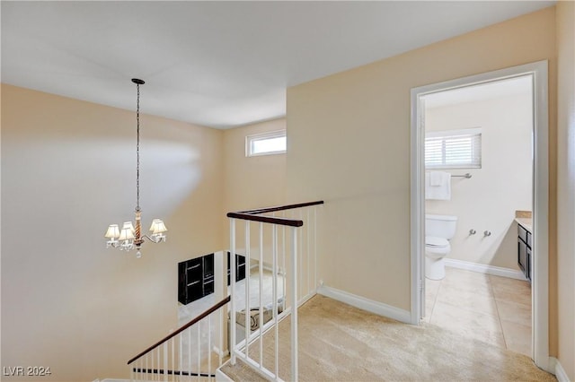 hallway with light colored carpet, a healthy amount of sunlight, and a notable chandelier